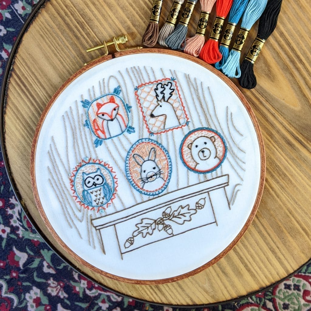 folksy embroidery hoop art pictured on table with embroidery floss