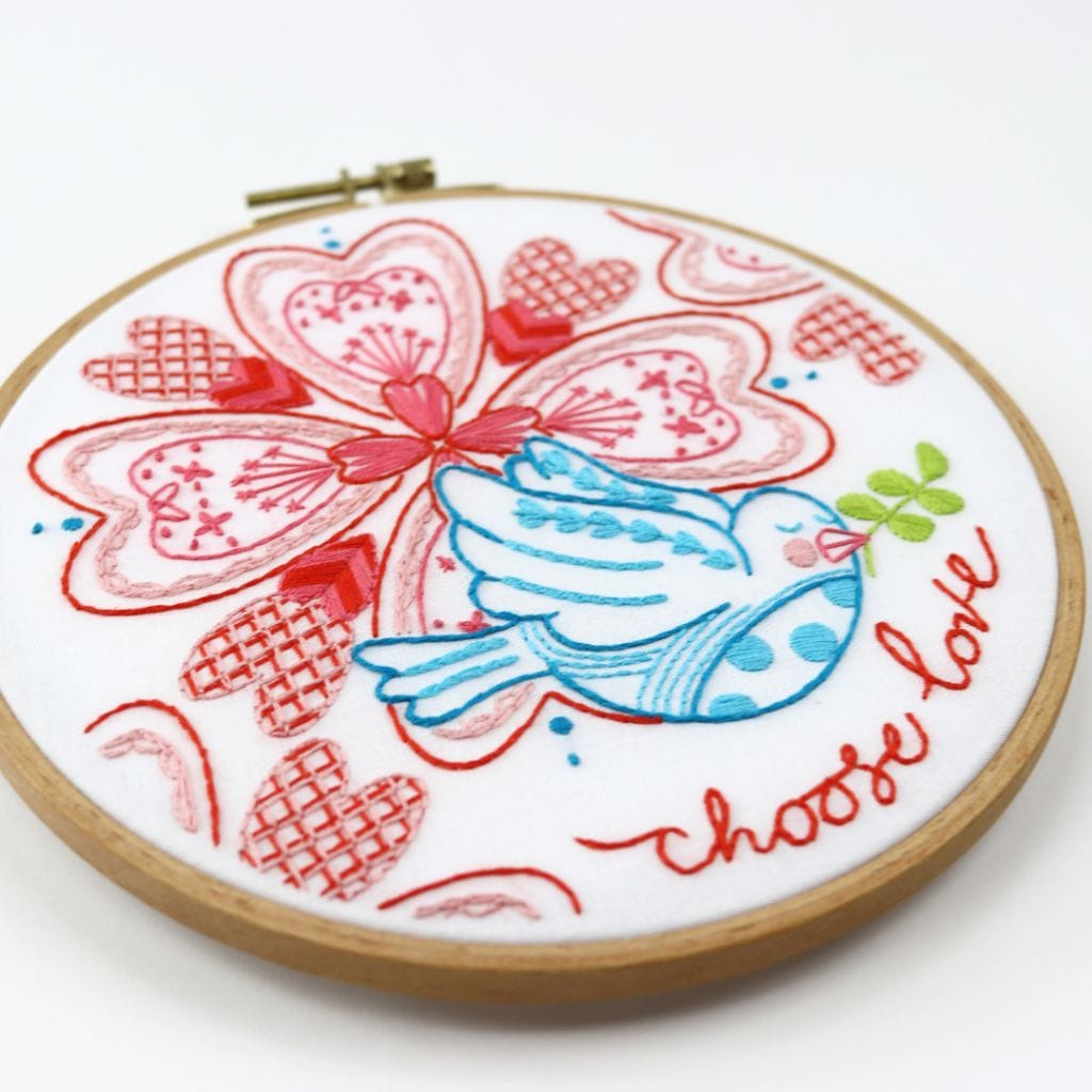 Embroidered hoop art with love or Valentine theme. Nested hearts in mandala design with blue dove and "choose love" message.