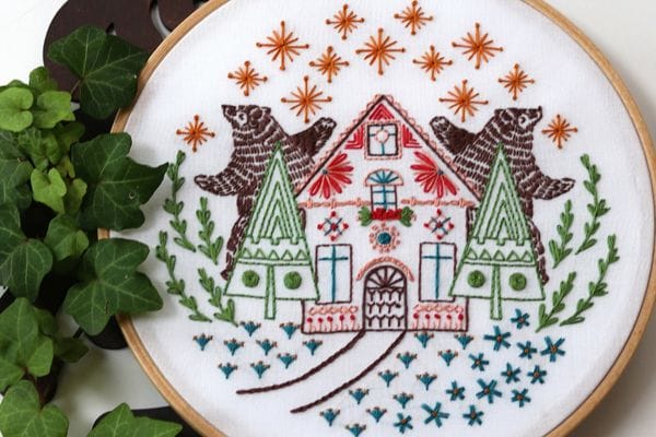 embroidery project with bears dancing under the stars in front of Christmas-styled cottage