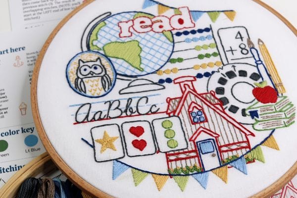 embroidery project with school-themed motifs including globe, flashcards, abacus, owl, books, apple and a vintage schoolhouse 