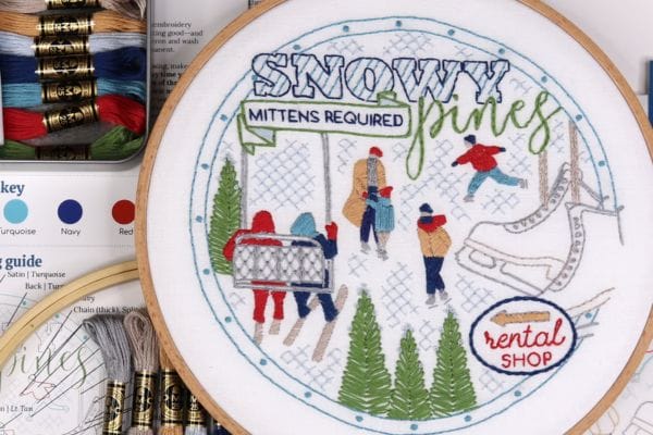Embroidered hoop art of snowy pines and skiing