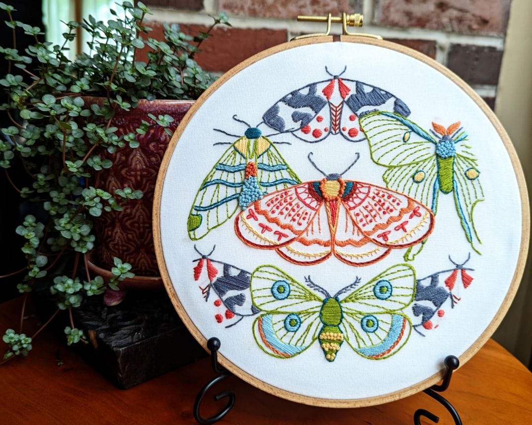 embroidery hoop art with moth motif displayed on stand