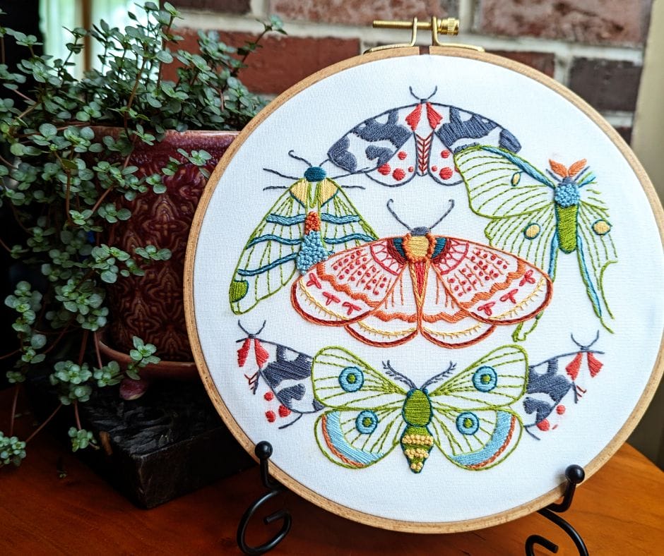 displayed embroidery hoop art with moth motif